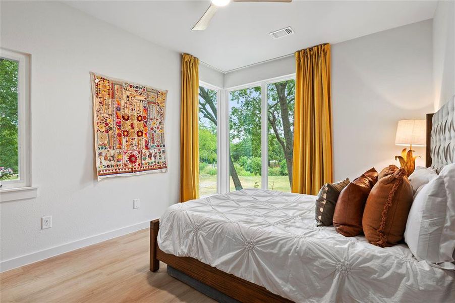 Bedroom with multiple windows, light wood-type flooring, and ceiling fan