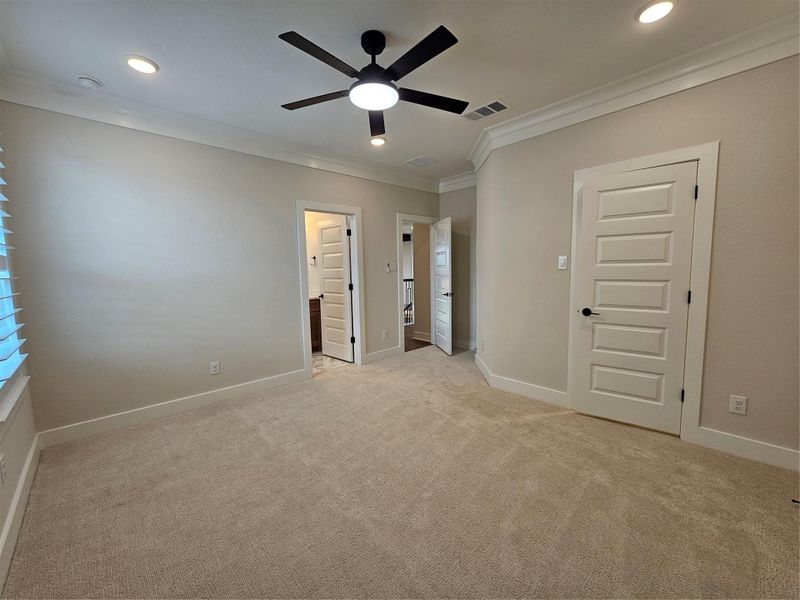 This bright, spacious bedroom features neutral walls, plush carpeting, recessed lighting, and a modern ceiling fan. It includes two doors, one leading to a bathroom and another for storage, offering convenience and functionality. This bright, spacious bedroom features neutral walls, plush carpeting, recessed lighting, and a modern ceiling fan. It includes two doors, one leading to a bathroom and another for storage, offering convenience and functionality.