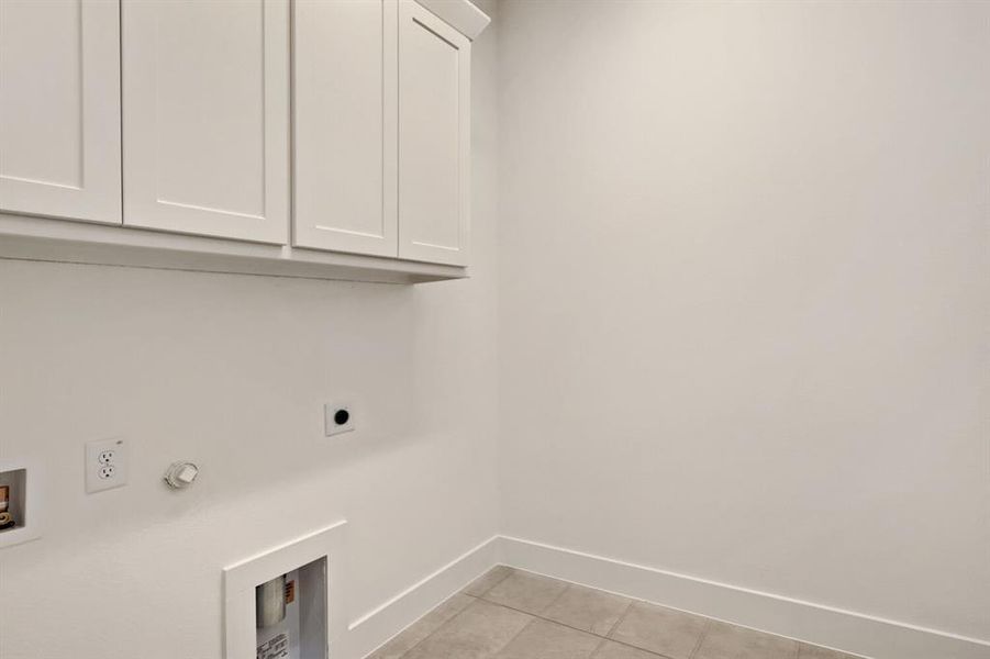 Laundry area with cabinet space, light tile patterned floors, hookup for a gas dryer, hookup for an electric dryer, and hookup for a washing machine