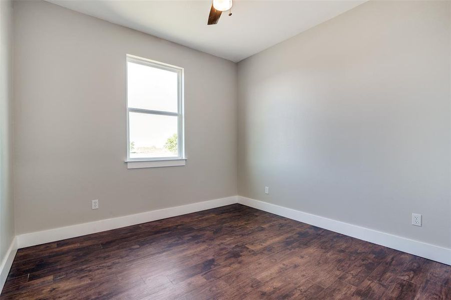 Empty room with ceiling fan and dark hardwood / wood-style floors