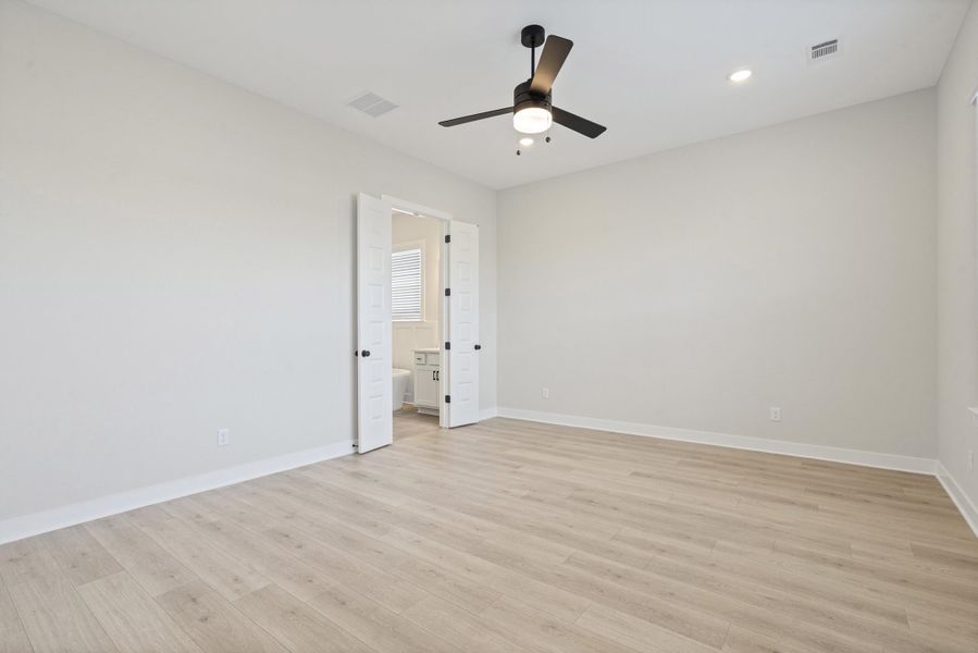 Spacious room featuring wood-finish flooring, light gray wall paint, and white baseboards Spacious room featuring wood-finish flooring, light gray wall paint, and white baseboards