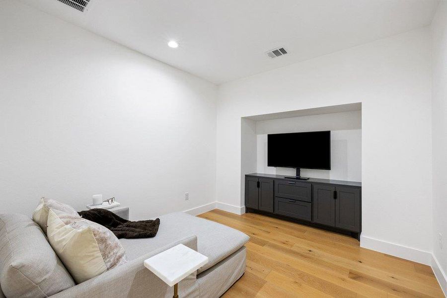 Streamlined entertainment area with a built-in media console and warm wood flooring. Streamlined entertainment area with a built-in media console and warm wood flooring.