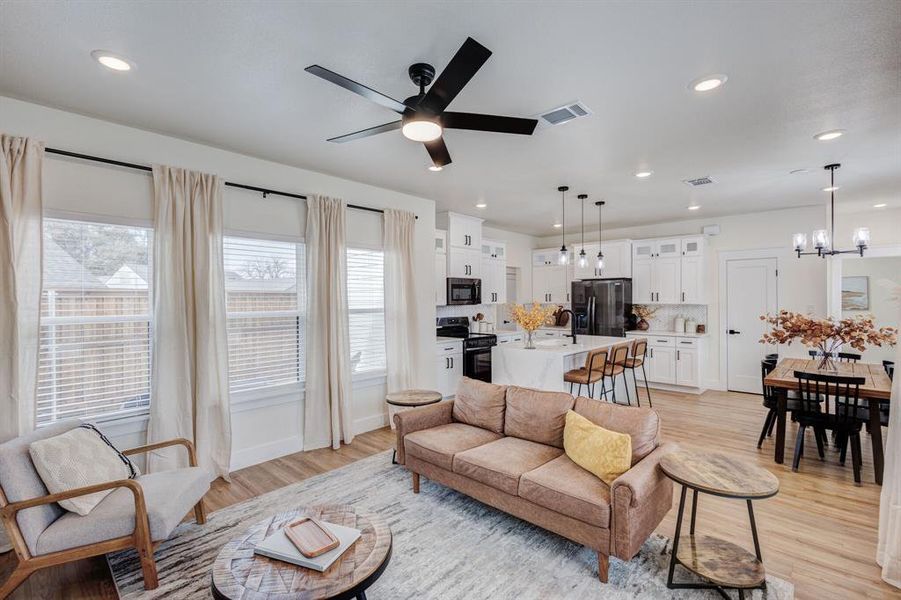 Living room featuring sink, ceiling fan with notable chandelier, and light hardwood / wood-style floors Living room featuring sink, ceiling fan with notable chandelier, and light hardwood / wood-style floors