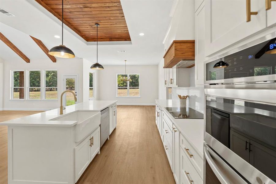 Kitchen with white cabinetry, light wood-type flooring, healthy amount of natural light, decorative light fixtures, and wood ceiling