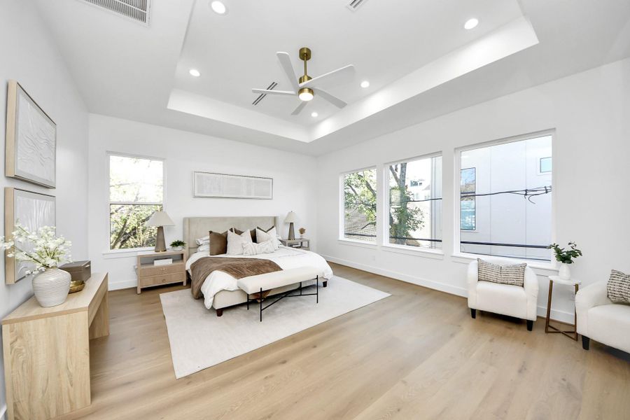 Spacious primary bedroom with tray ceiling, recessed lighting, and oversized windows!