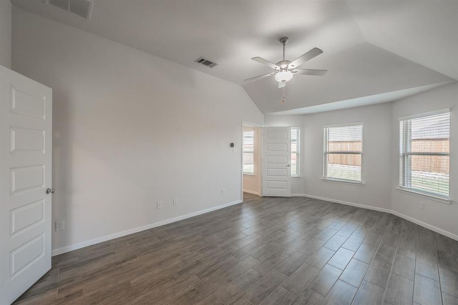 Spare room with vaulted ceiling, dark wood-style floors, and a ceiling fan Spare room with vaulted ceiling, dark wood-style floors, and a ceiling fan