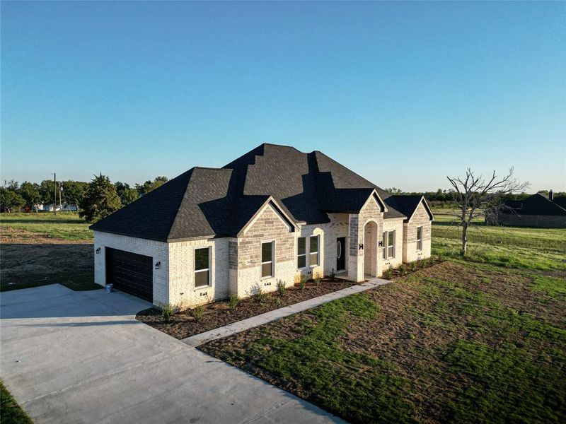 French provincial home with a garage and a front lawn