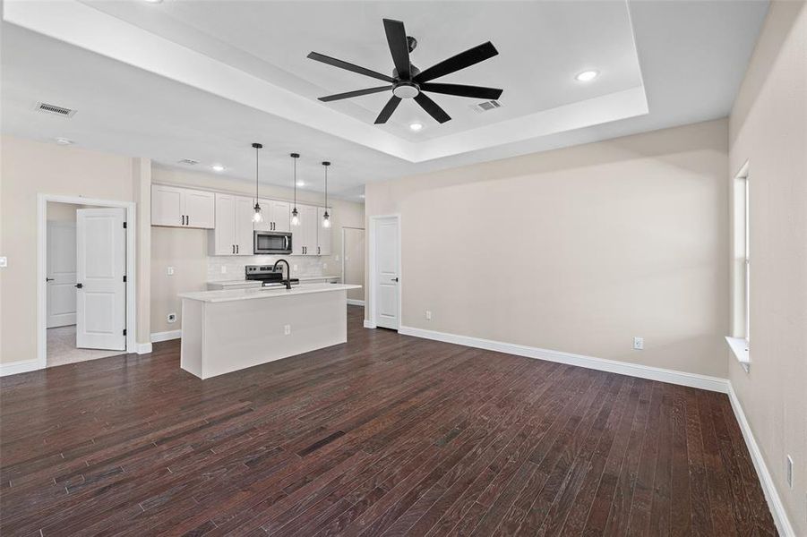 Open-concept living area featuring dark wood-finish flooring, a contemporary ceiling fan, and recessed lighting