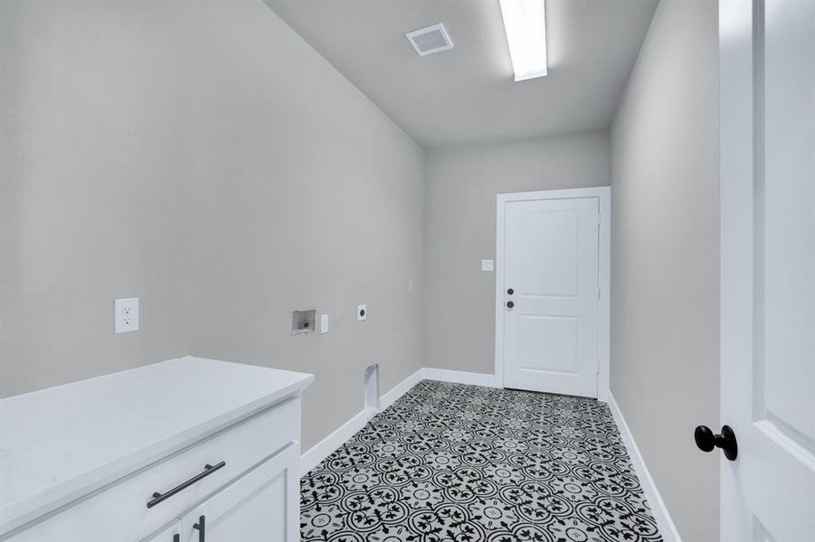 Washroom with cabinets, light tile patterned floors, hookup for an electric dryer, and washer hookup