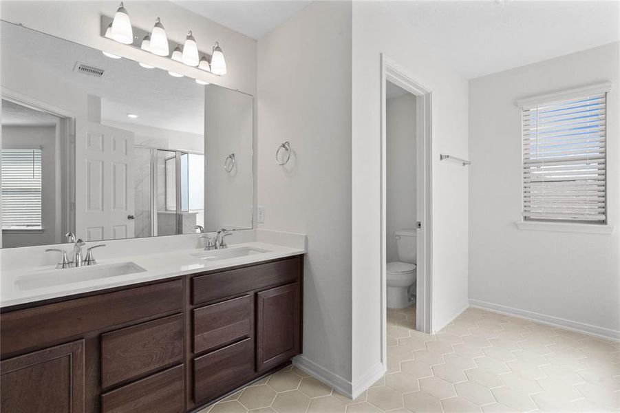 This large primary bath is spacious enough to share! With separate vanities, plentiful cabinet and counter space, you are sure to have private area while sharing this bathroom!