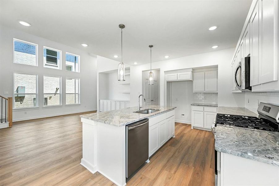 Kitchen with tasteful backsplash, light stone countertops, stainless steel appliances, light wood-type flooring, and recessed lighting