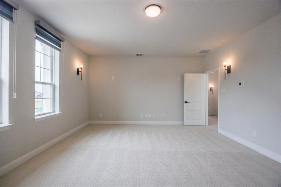 Empty room featuring light colored carpet, visible vents, and baseboards