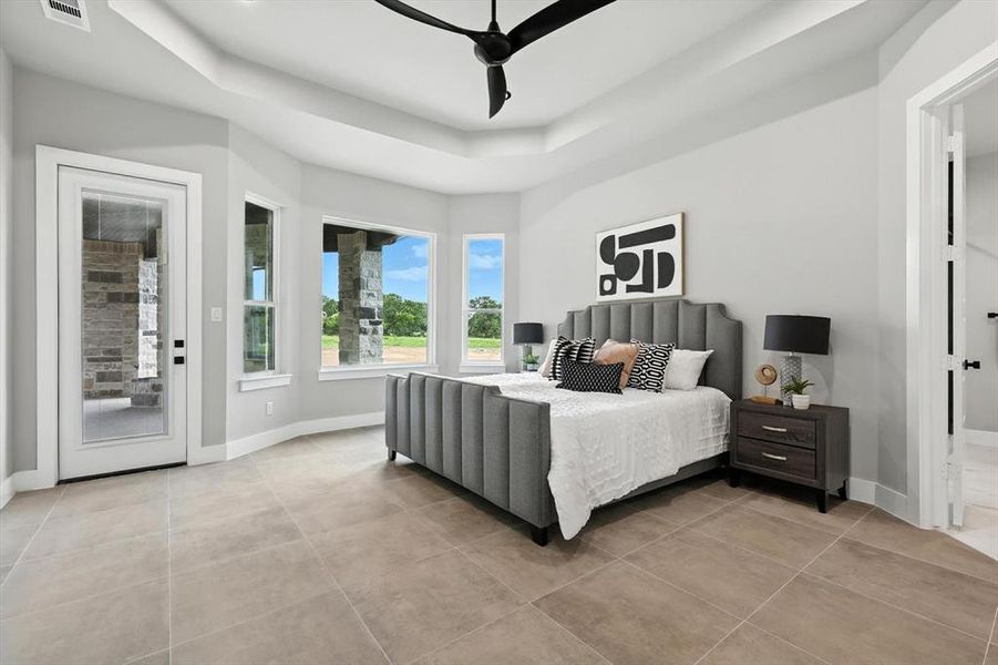 Bedroom with a tray ceiling, light tile patterned flooring, access to outside, and ceiling fan