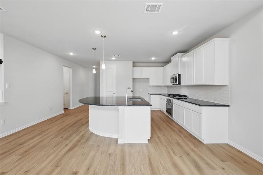 Kitchen featuring visible vents, stainless steel appliances, light wood-style floors, and a sink Kitchen featuring visible vents, stainless steel appliances, light wood-style floors, and a sink