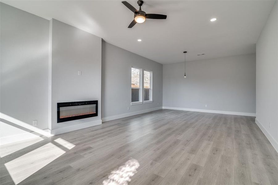 Unfurnished living room featuring ceiling fan and light wood-type flooring