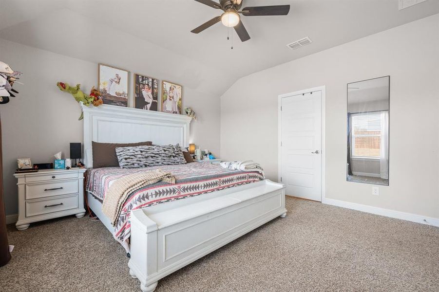 Bedroom with light carpet, vaulted ceiling, and ceiling fan Bedroom with light carpet, vaulted ceiling, and ceiling fan