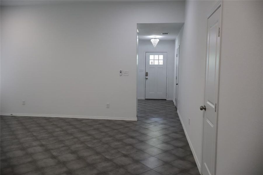 Foyer featuring a white front door with multiple window panes, a crystal chandelier, and large format square tile flooring