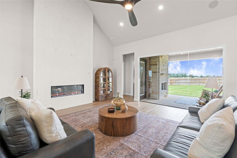 An inviting gathering space features an electric fireplace, hardwood flooring, and seamless access to the outdoor living area. An inviting gathering space features an electric fireplace, hardwood flooring, and seamless access to the outdoor living area.
