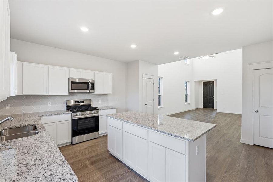 Kitchen featuring white cabinetry, light-colored countertops, stainless steel appliances, and a hexagon-patterned backsplash Kitchen featuring white cabinetry, light-colored countertops, stainless steel appliances, and a hexagon-patterned backsplash