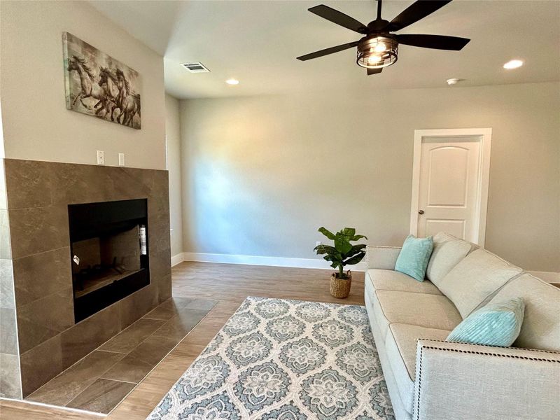 Living room featuring ceiling fan, recessed lighting, a tile fireplace, and light wood-type flooring Living room featuring ceiling fan, recessed lighting, a tile fireplace, and light wood-type flooring