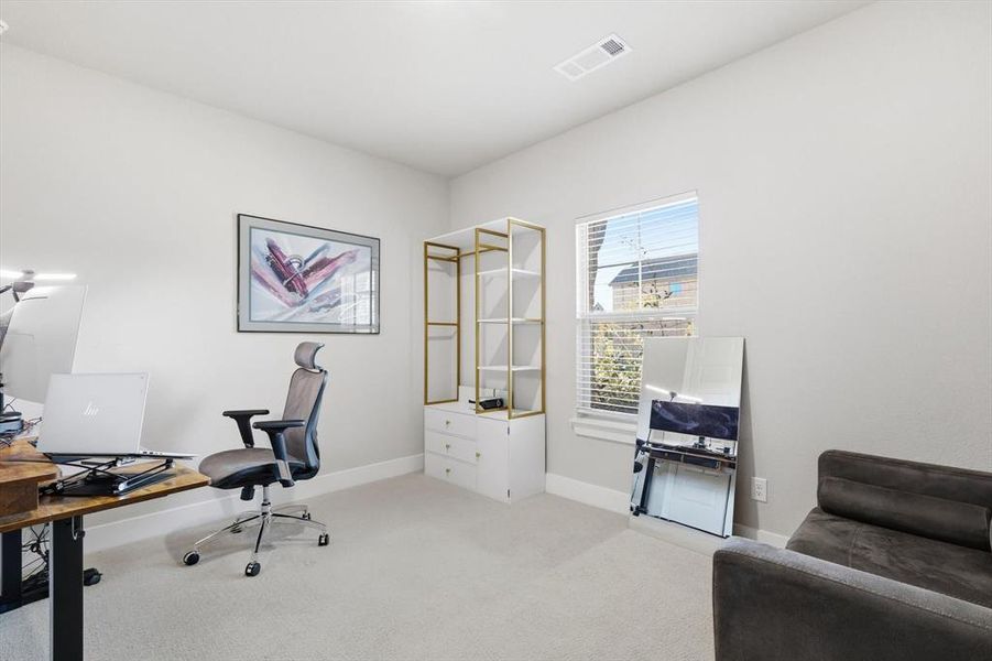 Home office with light colored carpet and baseboards
