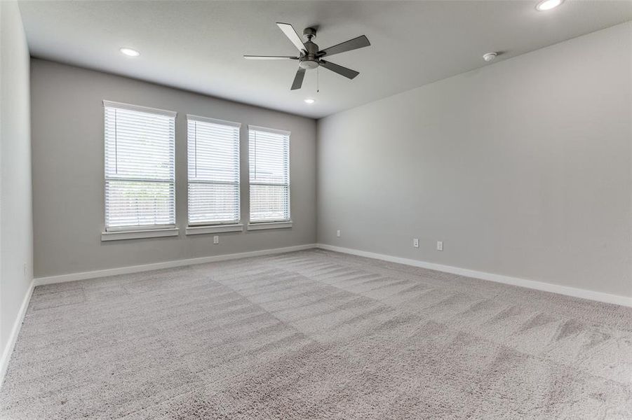 Carpeted spare room featuring ceiling fan