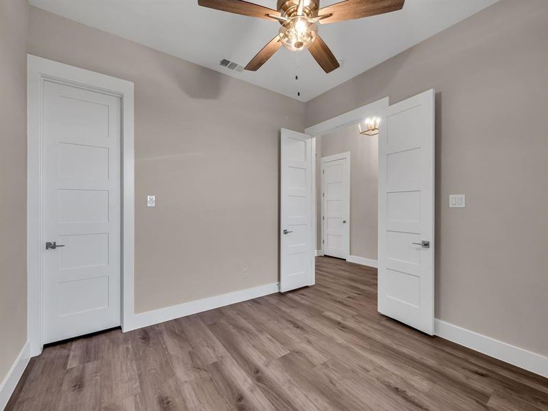 Unfurnished bedroom with light hardwood / wood-style floors and ceiling fan with notable chandelier