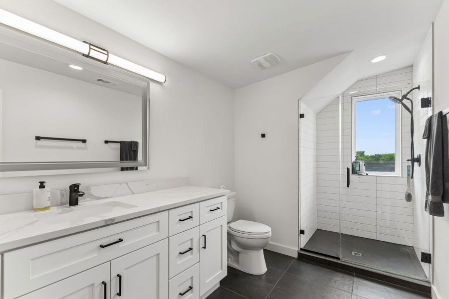 Bathroom featuring a spacious vanity with white cabinetry, a light-toned countertop, and an integrated sink with a black faucet
