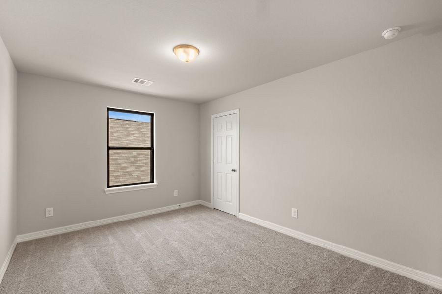 The second bedroom features plush carpet, fresh paint and a large window.