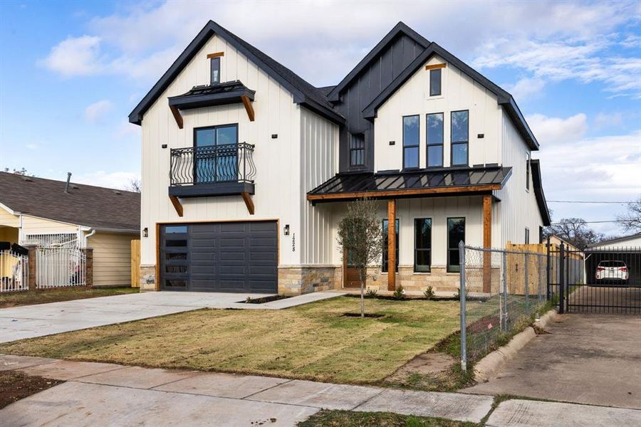 Modern farmhouse style home featuring a balcony, a garage, and a front lawn