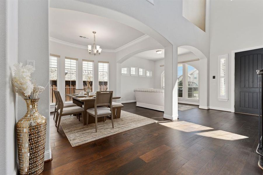 Dining room featuring dark hardwood / wood-style floors, crown molding, and a chandelier