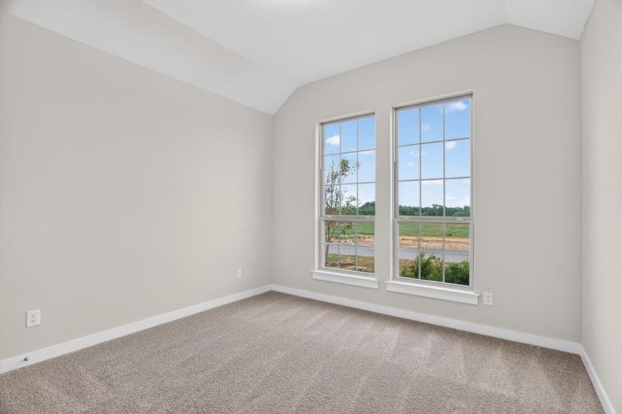 Vaulted ceiling room with two multi-pane windows, neutral wall paint, and plush carpet flooring