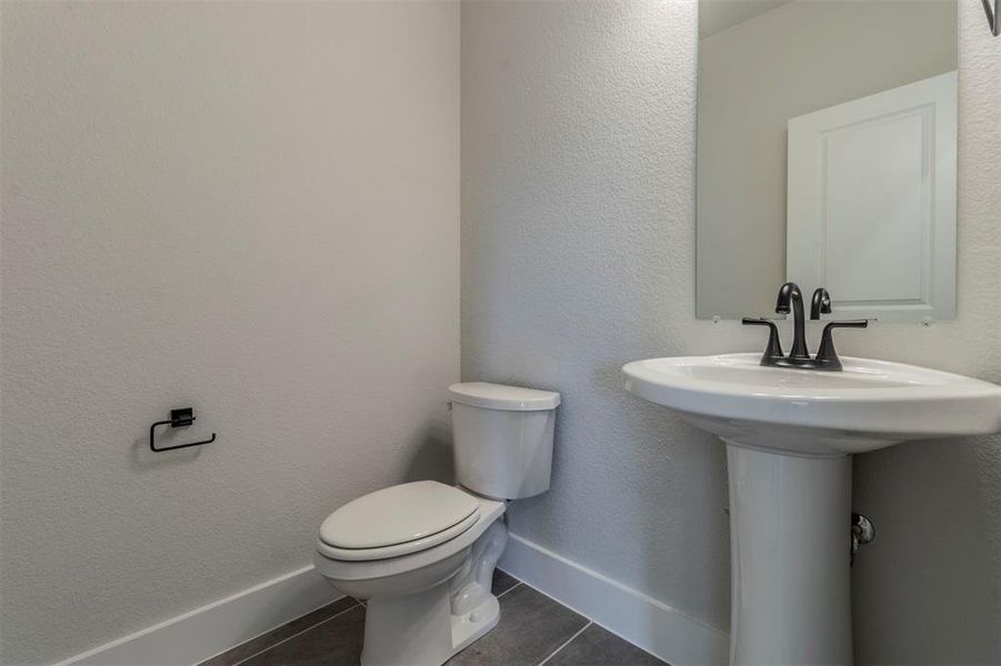 Bathroom with dark tile patterned flooring and a textured wall