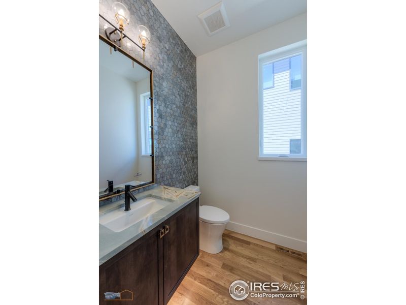 Main Floor Powder Room Features Floating Cabinet, Large Mirror And Tiled Wall