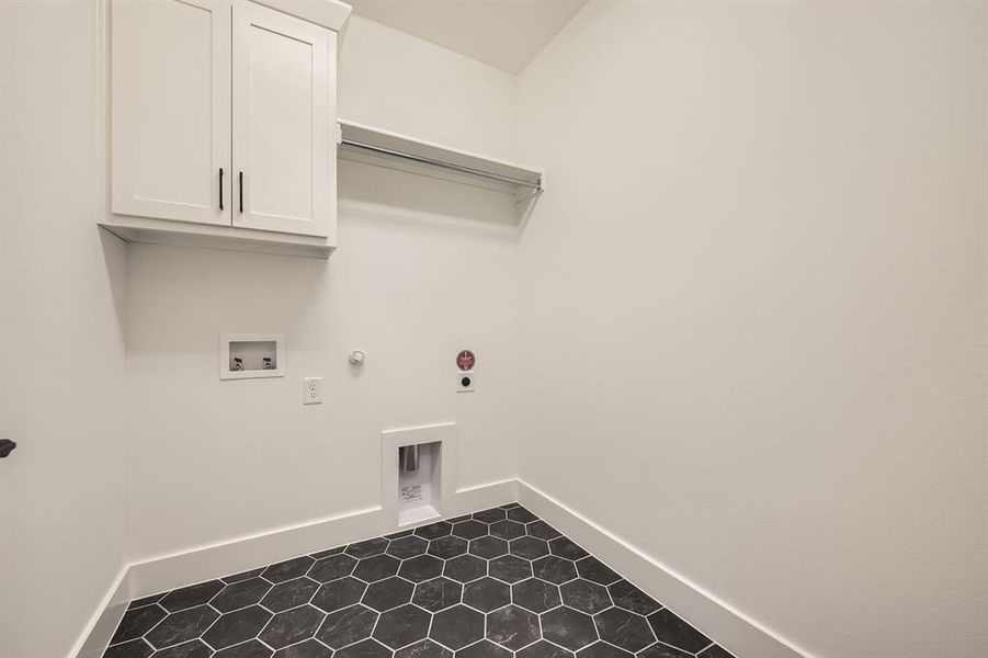 Laundry room with hookup for a gas dryer, hookup for a washing machine, baseboards, and dark tile patterned floors