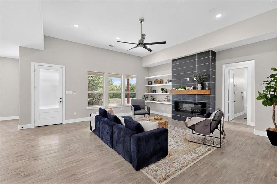 Living area with a fireplace, built in shelves, a ceiling fan, light wood finished floors, and recessed lighting