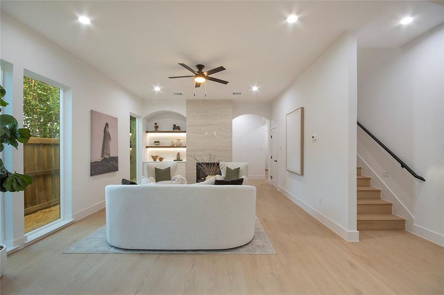 Living room featuring light wood-type flooring, recessed lighting, ceiling fan, built in features, and stairway