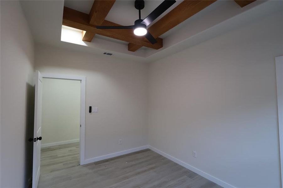 Spare room with beam ceiling, a ceiling fan, and light wood finished floors