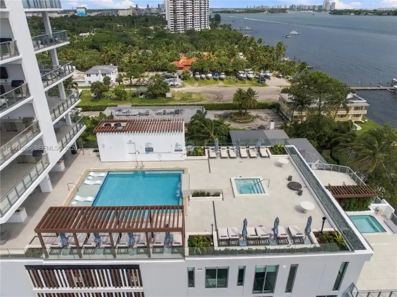 Elevated terrace featuring a pool, integrated spa, wood-slat pergola, and stone-finish decking Elevated terrace featuring a pool, integrated spa, wood-slat pergola, and stone-finish decking
