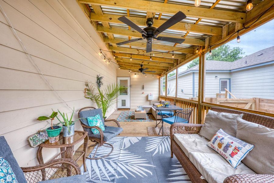 Expansive covered patio featuring wood-finish decking, exposed wood beam ceiling, multiple ceiling fans, and string lighting