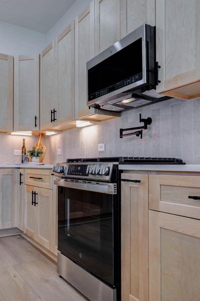 Designer kitchen featuring a custom wood vent hood, pot filler, and quartz countertops Designer kitchen featuring a custom wood vent hood, pot filler, and quartz countertops