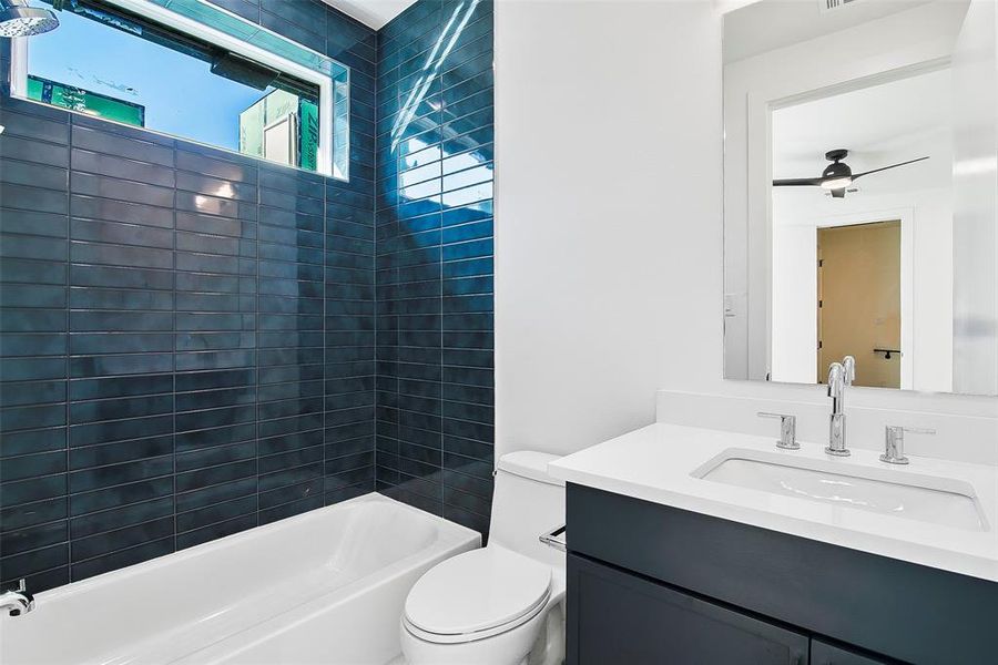 Full bathroom featuring tiled shower / bath, vanity, toilet, and ceiling fan