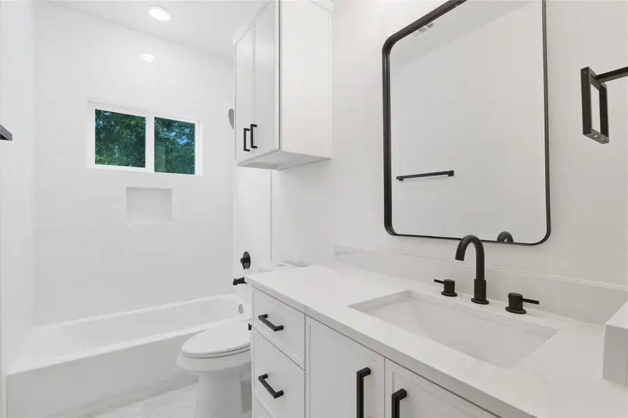 This stunning upstairs full bath offers a fresh, modern design with a clean white vanity, quartz counters, and matte black hardware. A combination shower and tub makes the space practical for busy mornings and relaxing evenings alike. With built-in storage and timeless finishes, it’s a bathroom designed for your everyday comfort!