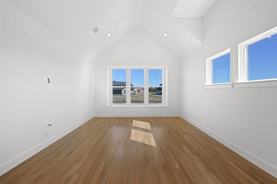 Empty room with high vaulted ceiling, wood finished floors, and recessed lighting Empty room with high vaulted ceiling, wood finished floors, and recessed lighting