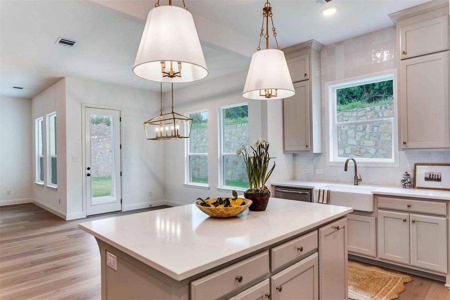 Kitchen with decorative backsplash, light wood-type flooring, hanging light fixtures, light stone counters, and recessed lighting