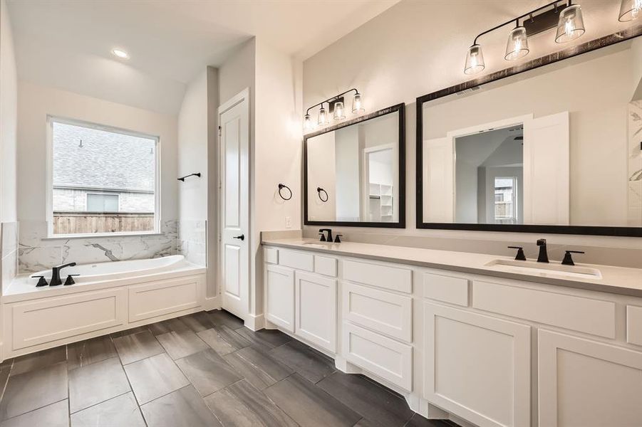 Bathroom featuring vanity, a tub, and vaulted ceiling