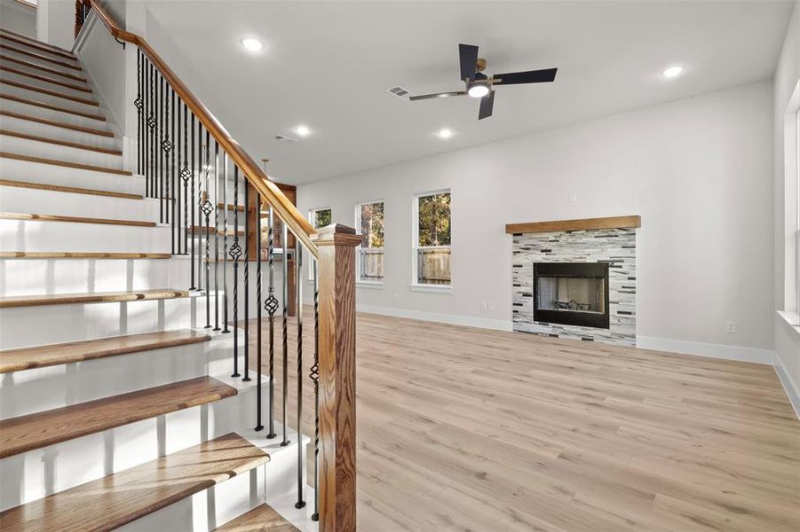 Unfurnished living room featuring ceiling fan, a fireplace, and light hardwood / wood-style flooring