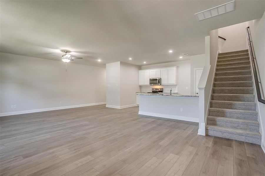 Unfurnished living room featuring recessed lighting, stairs, light wood finished floors, and ceiling fan Unfurnished living room featuring recessed lighting, stairs, light wood finished floors, and ceiling fan