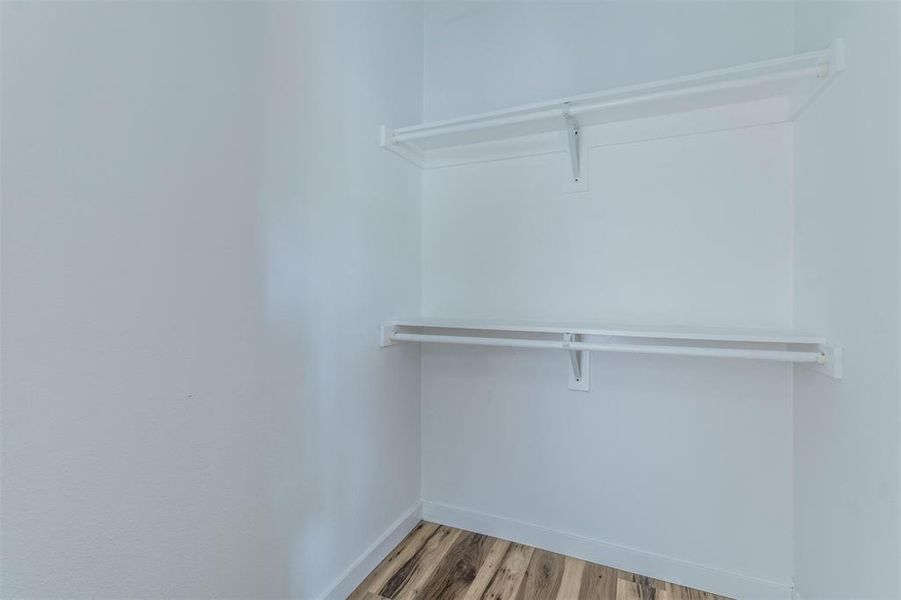 Walk in closet with light wood-style flooring Walk in closet with light wood-style flooring