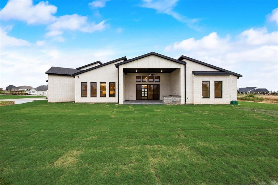 Back of house with a lawn, a ceiling fan, brick siding, and french doors Back of house with a lawn, a ceiling fan, brick siding, and french doors